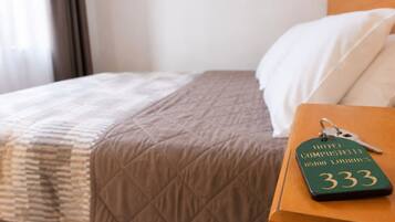 Habitación de hotel con cama, mesita de noche y llavero con el nombre del hotel y número de habitación.
