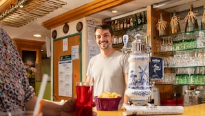 Eine Bar mit einer Theke, einer Flasche La semaine de quatre jours und einem dekorativen Gegenstand mit Windmühlenmuster.