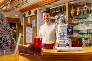 A bar area with a counter, a bottle of La semaine de quatre jours, and a windmill design on a decorative item. - Hôtel Compostelle (Lourdes)