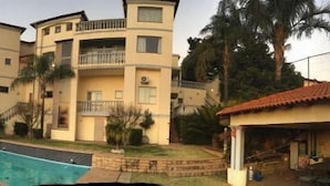 A multi-story residential building with balconies, a swimming pool, and surrounding greenery.