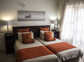 A hotel room with two beds, a headboard with a diamond pattern, and a wall-mounted elephant artwork. - Avalone Guest House (St. Lucia)