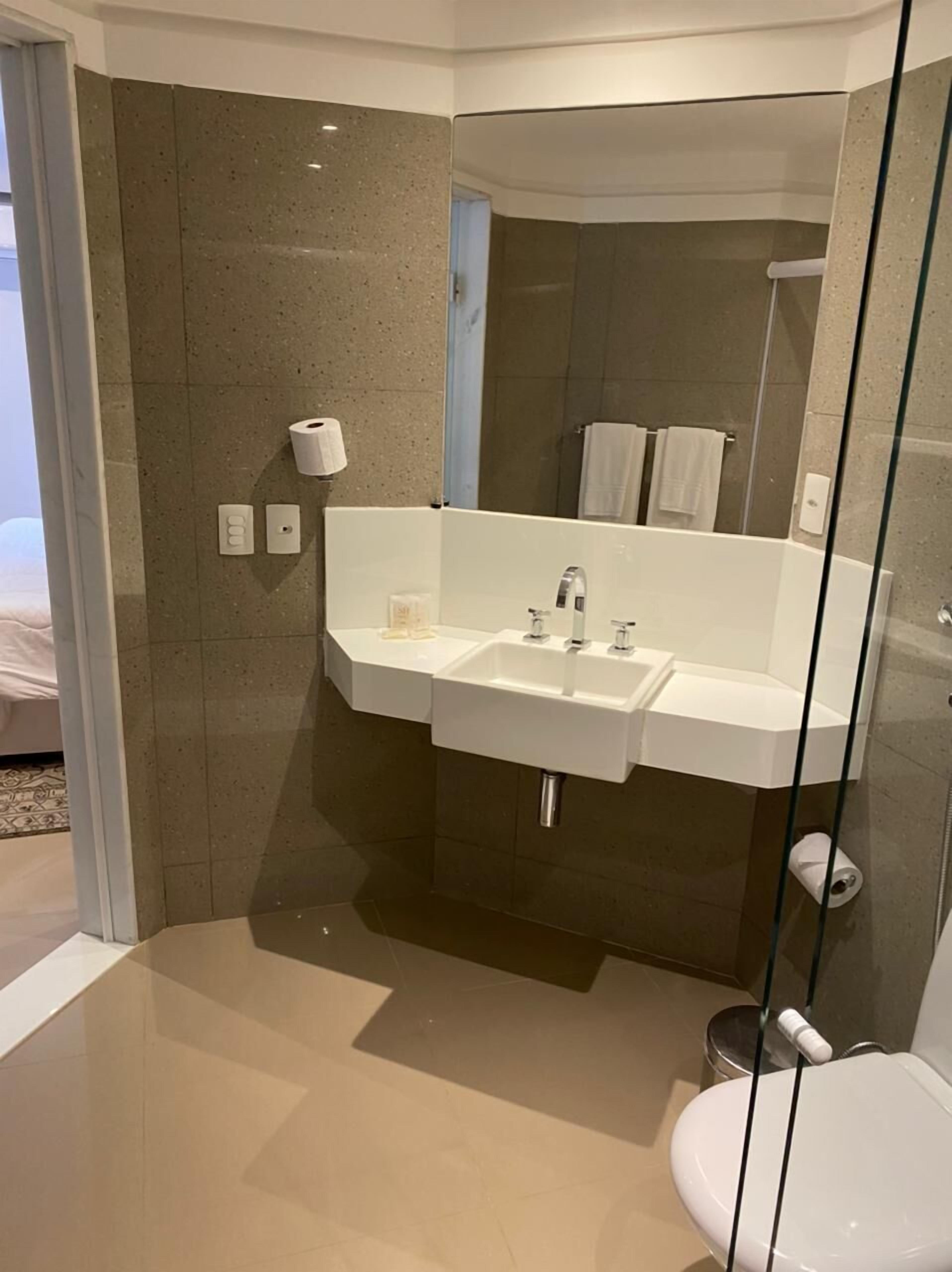 Une salle de bain moderne avec une douche à parois de verre, un meuble-lavabo à deux vasques et des toilettes.