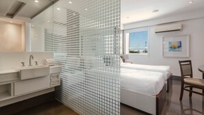 A modern hotel room with a large bed, a separate bathroom with a vanity, and a window offering a view. - DOM Barra Hotel (Rio de Janeiro)