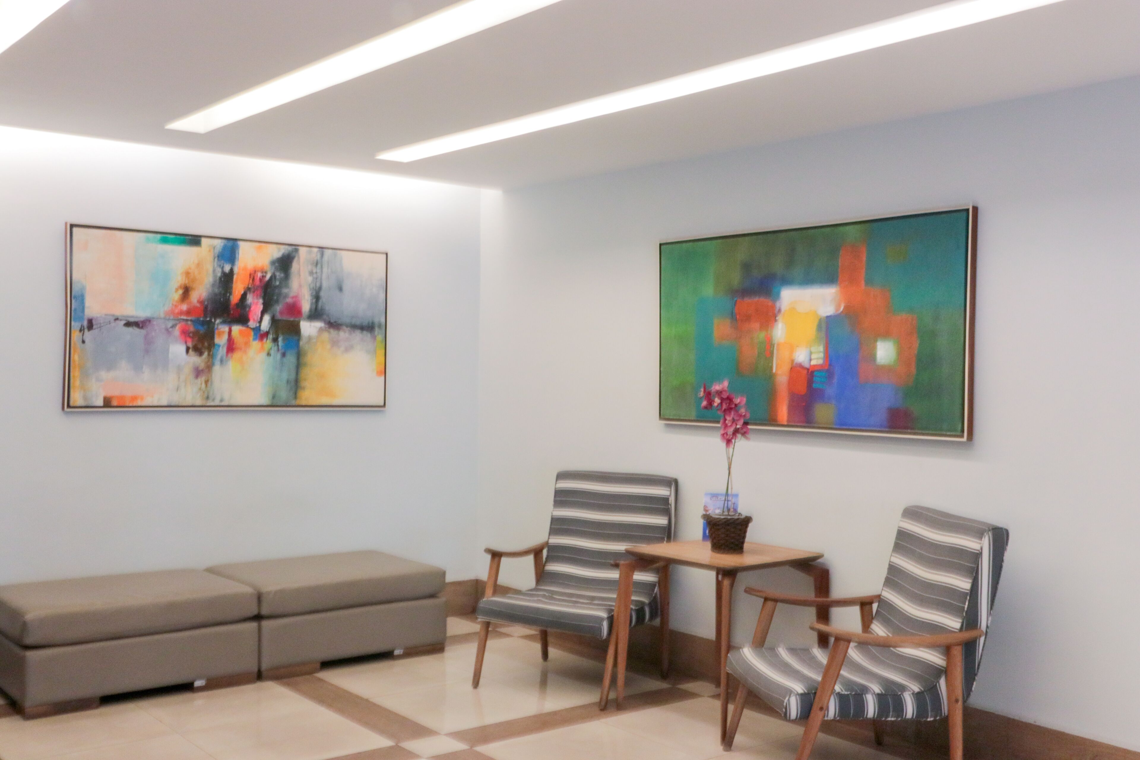 A modern waiting area with two striped chairs, a small table, and a bench.
