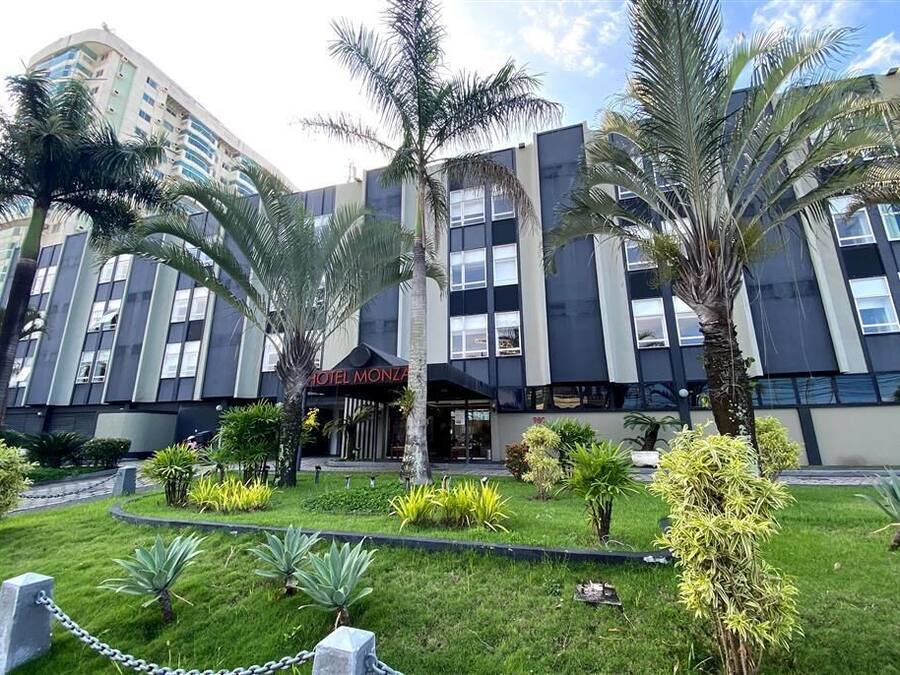 A modern hotel with a central entrance, surrounded by palm trees and well-maintained lawns.
