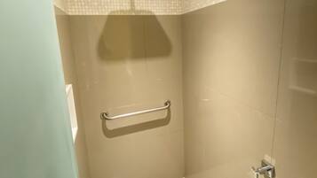 Ein kleines, modernes Badezimmer mit Dusche, Handlauf und Fliesenwand.