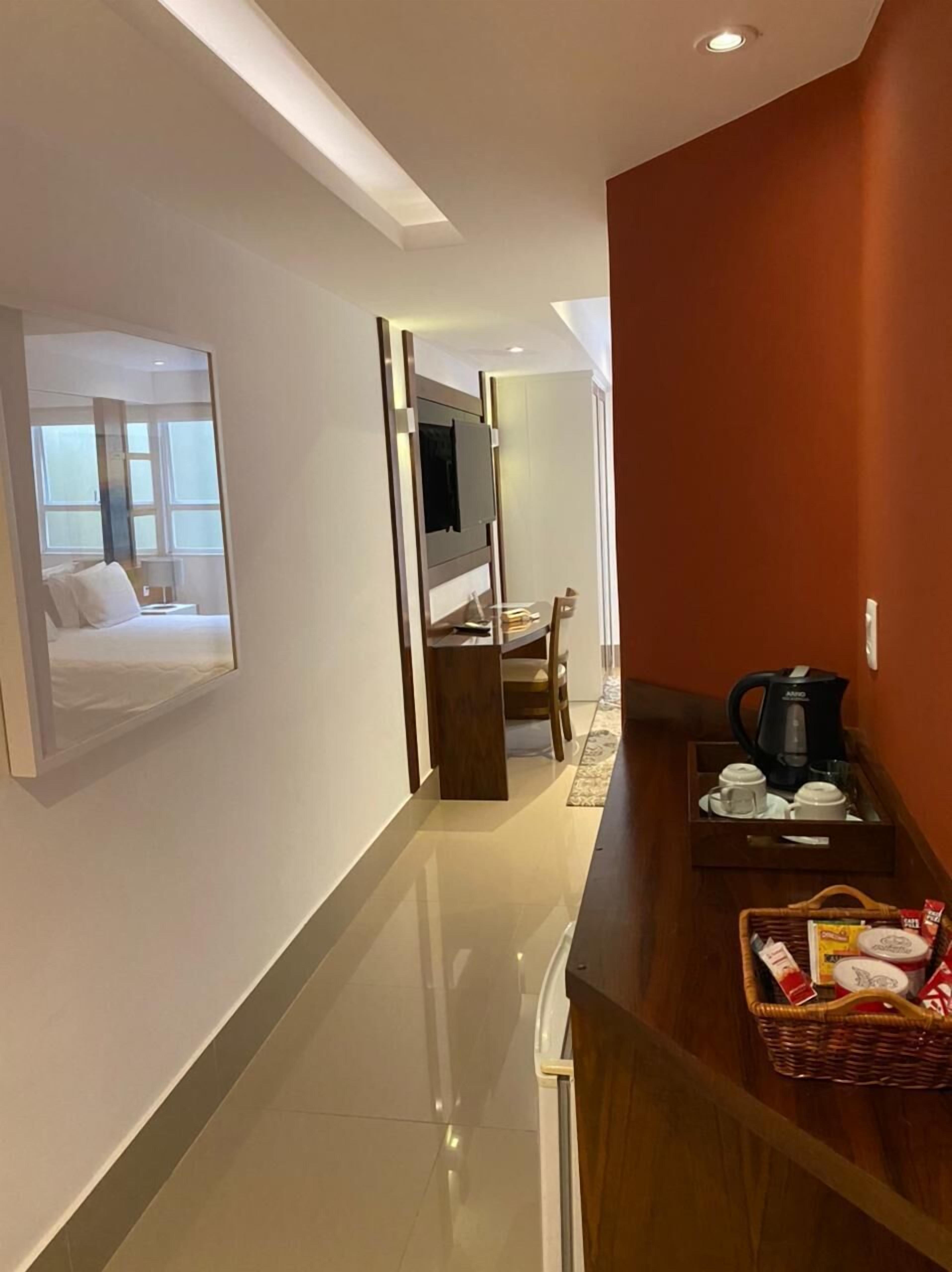 A hotel corridor with a wooden counter, a coffee maker, and a basket of toiletries.
