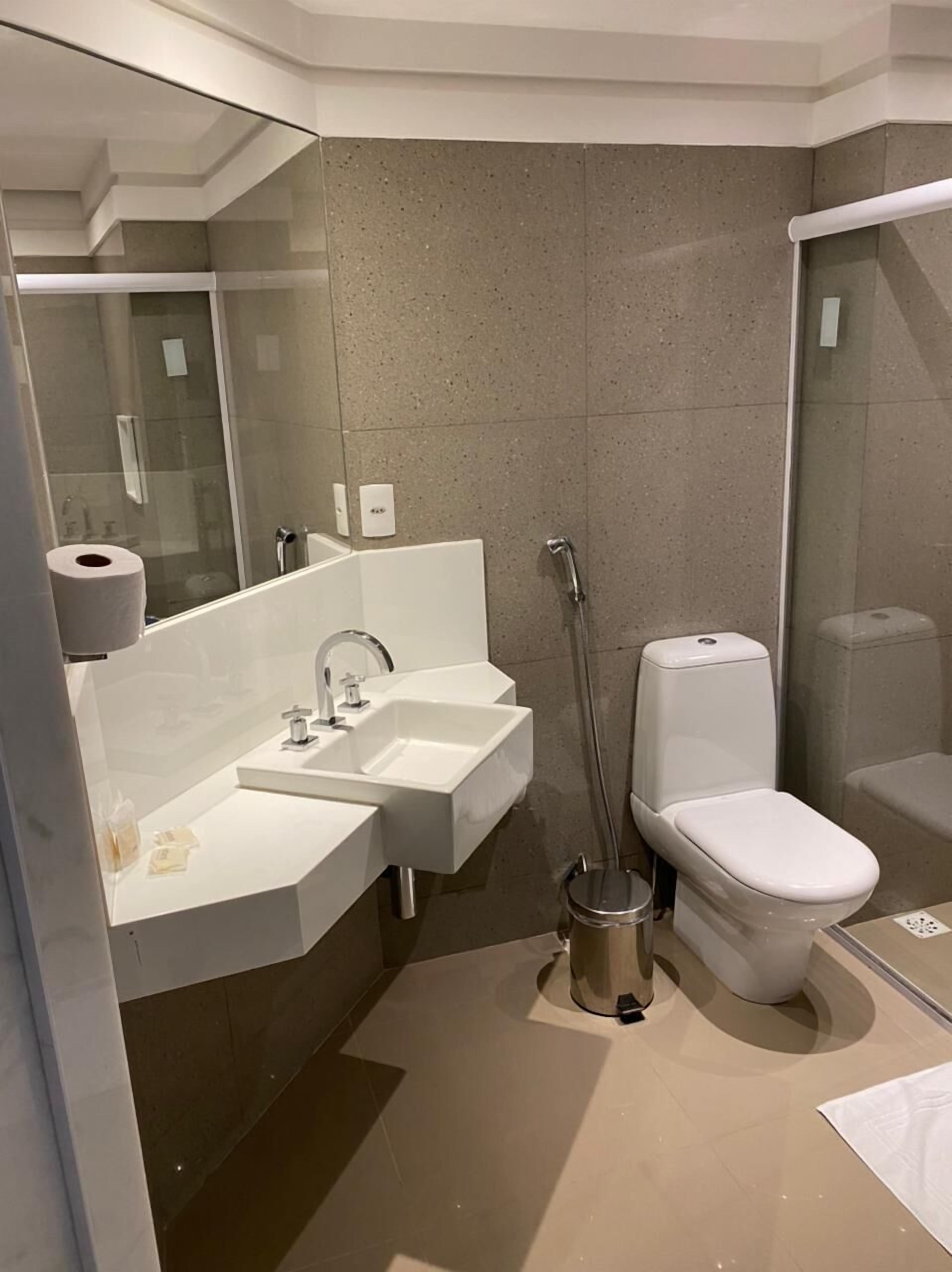 A modern bathroom with a dual sink vanity, a toilet, and a glass-enclosed shower.
