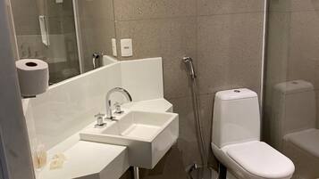 A modern bathroom with a dual sink vanity, a toilet, and a glass-enclosed shower.