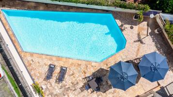 Una piscina al aire libre, sillones reclinables de piscina