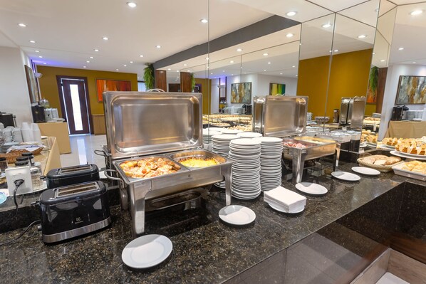 Un buffet avec différents stands de nourriture, notamment des plateaux de pâtisseries et un coin café.