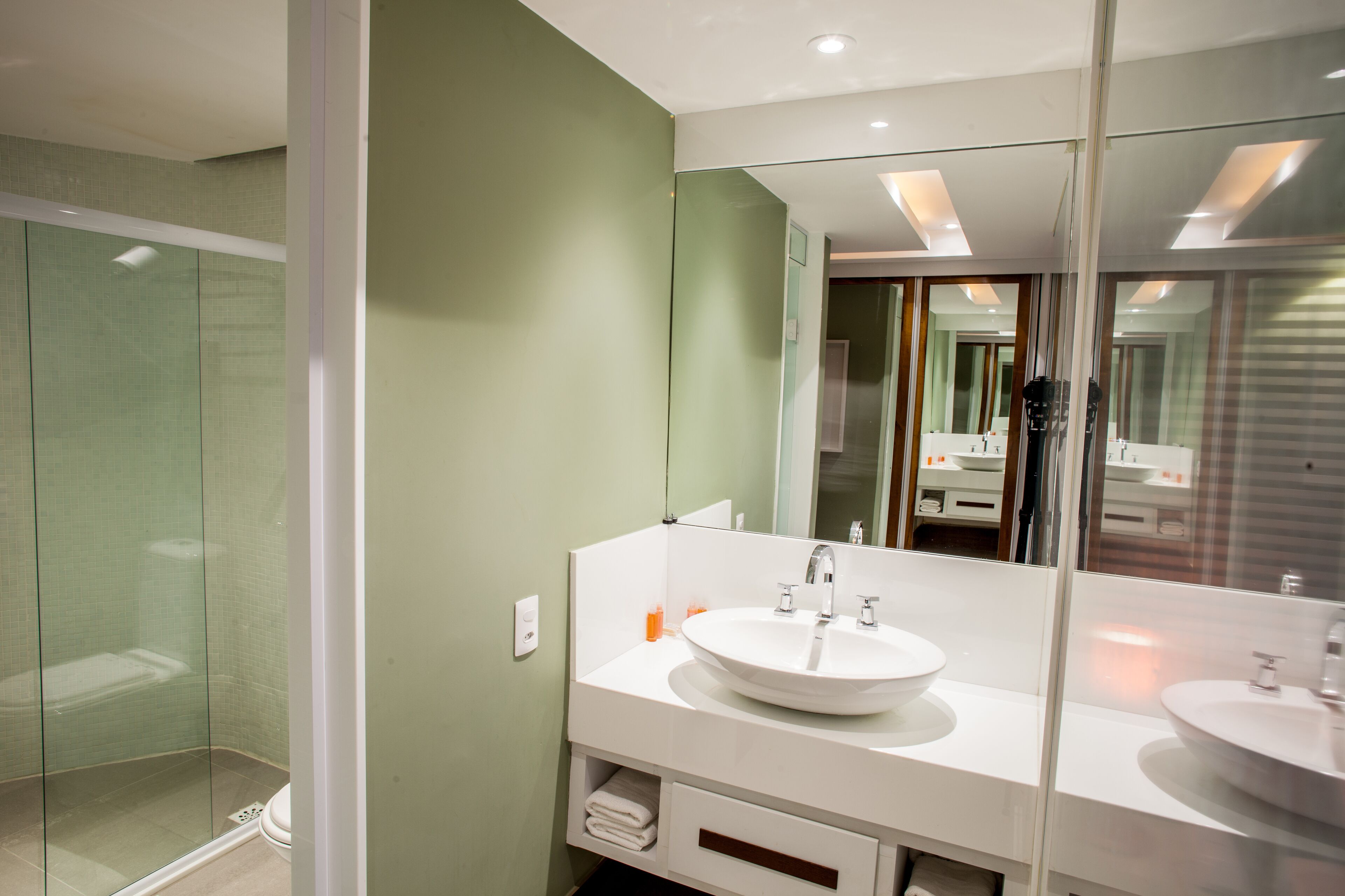 Un baño moderno con cabina de ducha de vidrio, un lavabo blanco y un espejo grande.