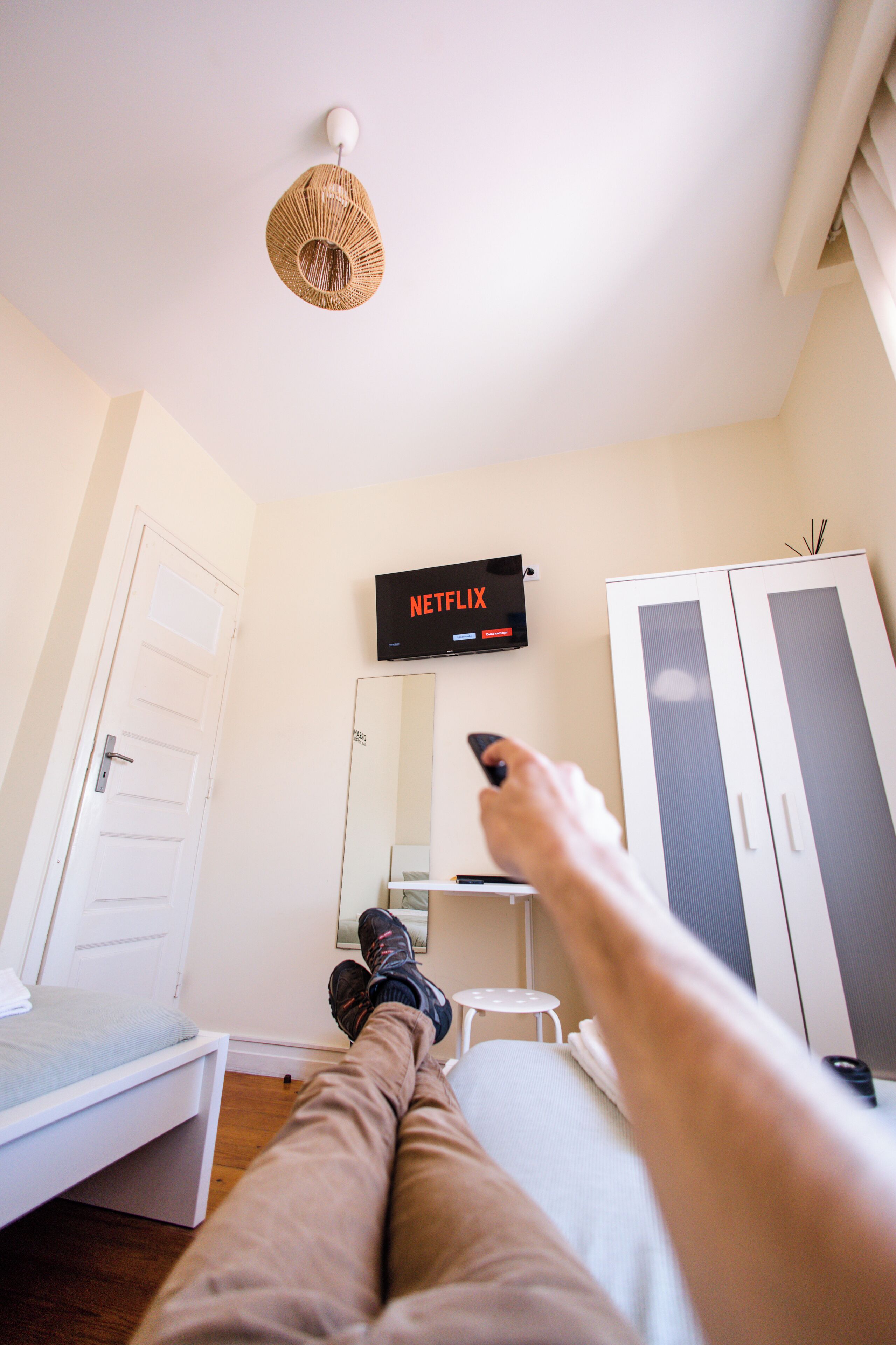 A room with a bed, a wardrobe, a TV displaying 'NETFLIX', and a small table.