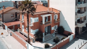 Un edificio de varios pisos con fachada roja, balcones y una palmera en primer plano.