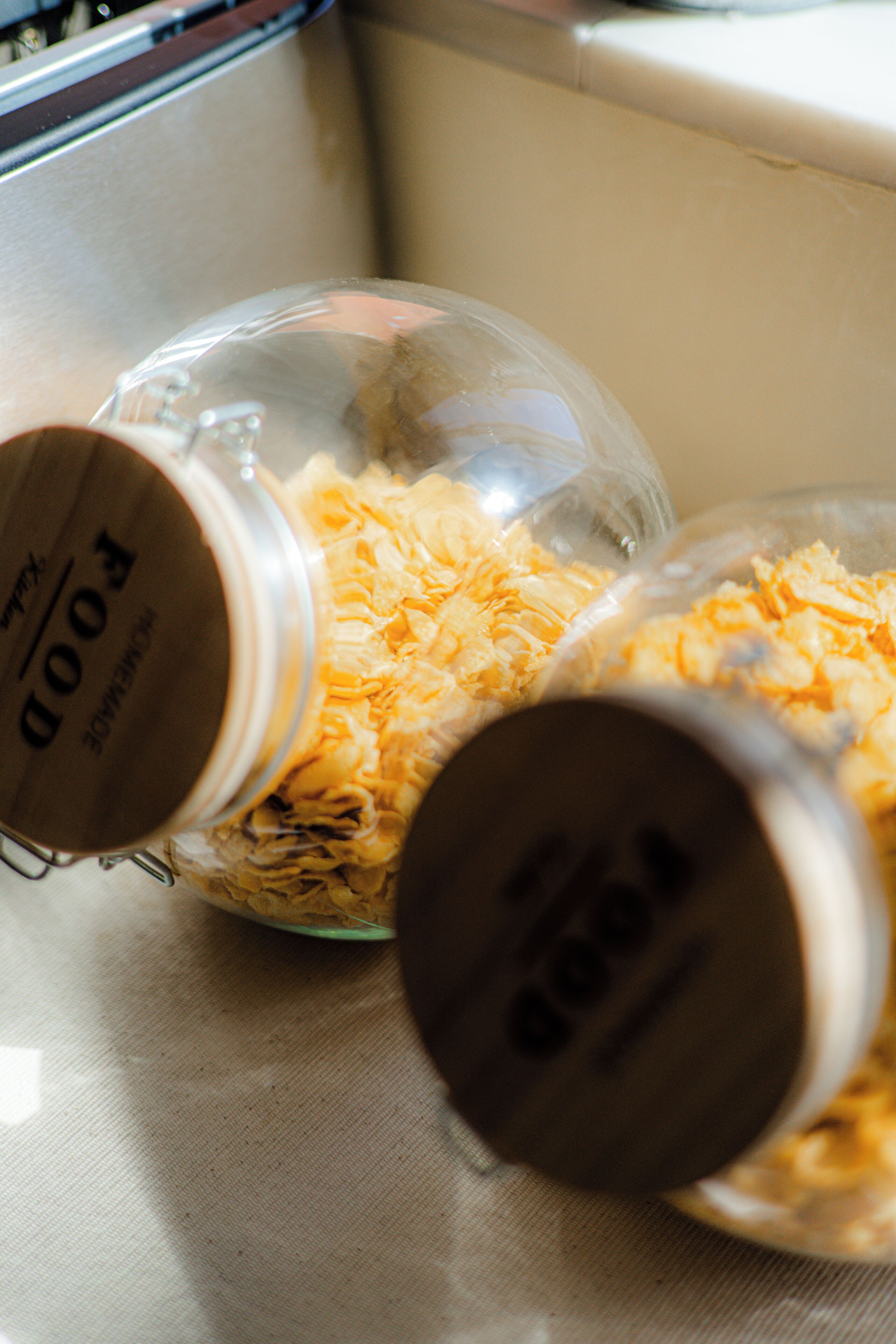 A close-up of two glass jars with metal lids, filled with shredded cheese, on a kitchen counter.