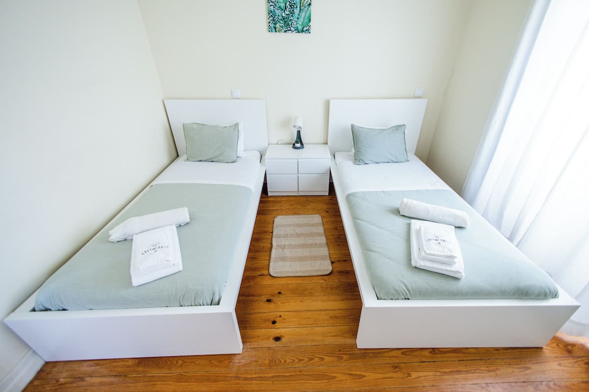A double room with two beds, a nightstand, and a small rug.