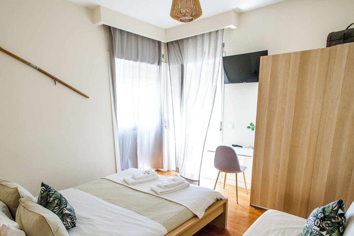 A modern bedroom with a bed, a chair, a desk, and a wardrobe.