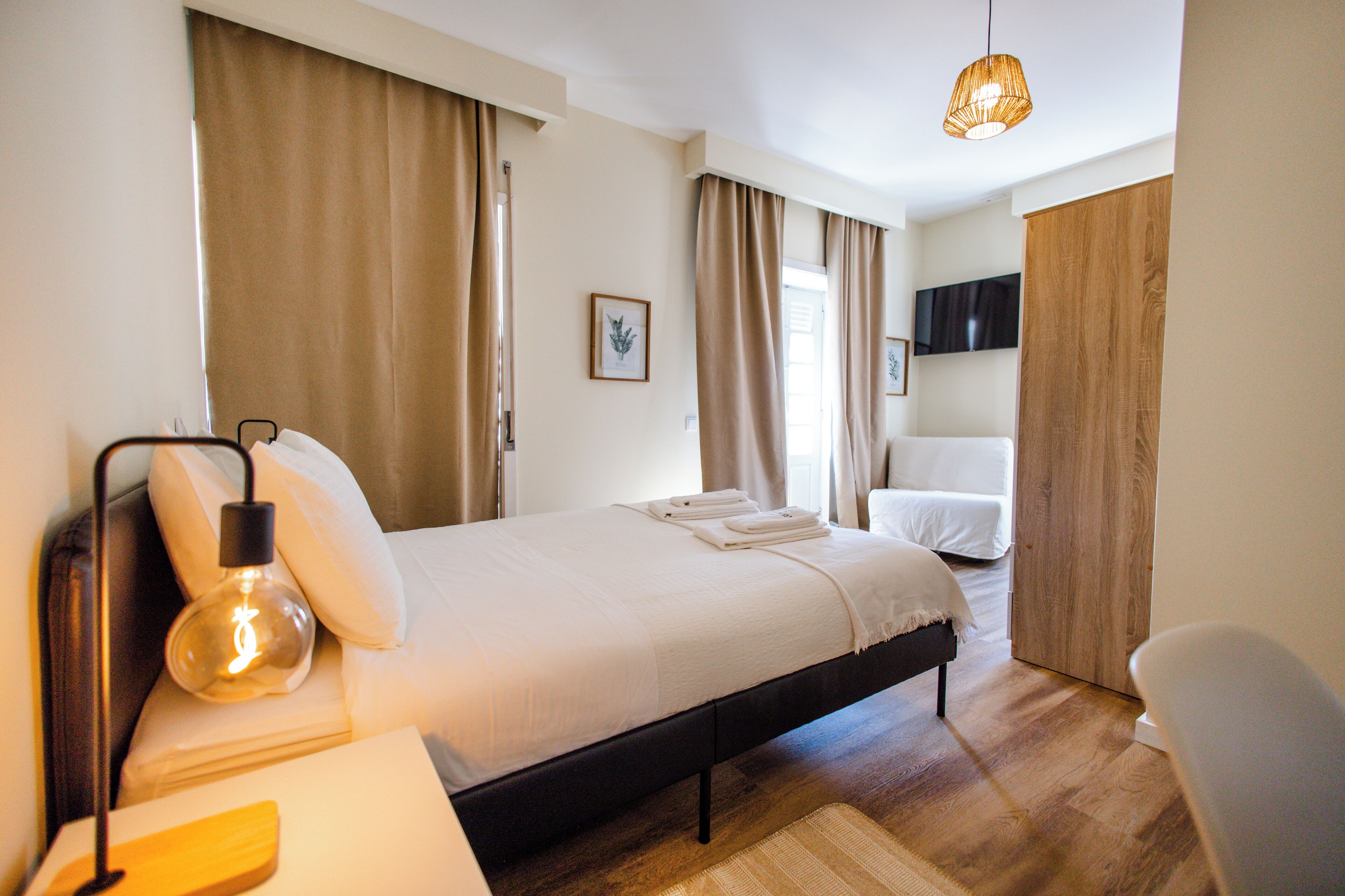 A modern bedroom with a bed, bedside lamp, and a TV mounted on the wall.