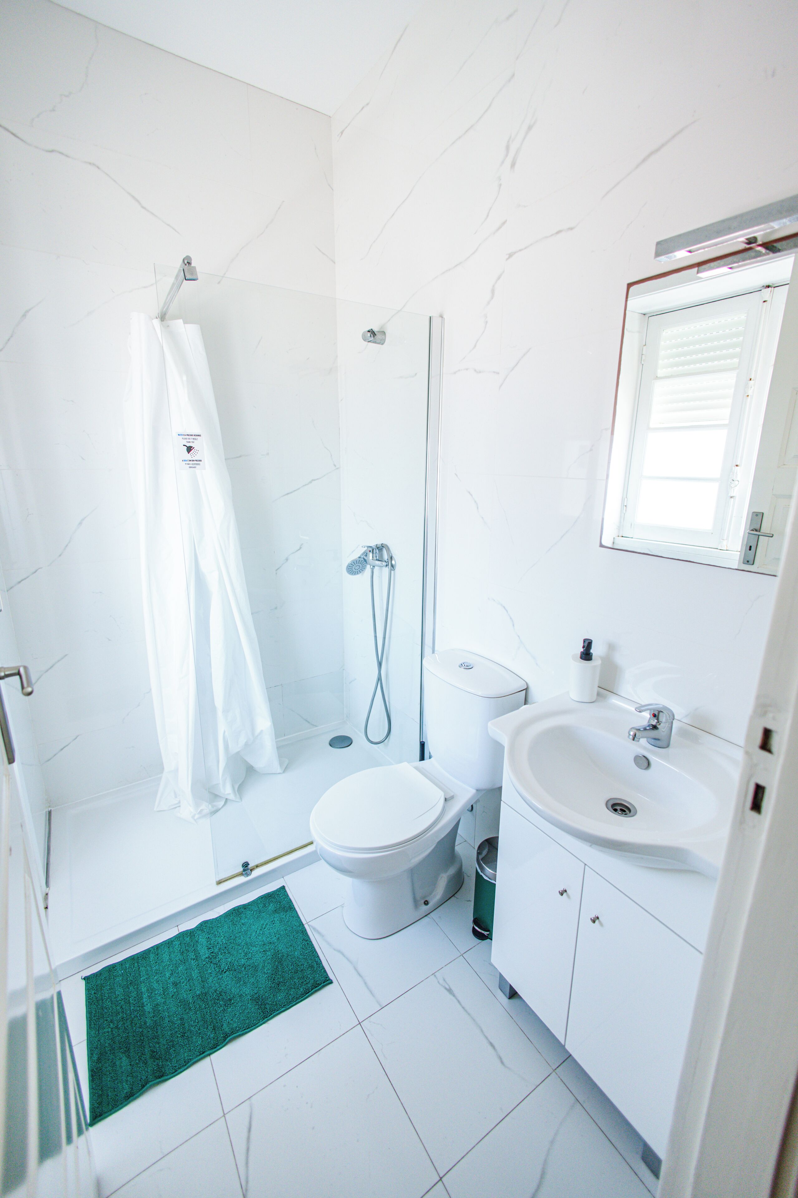 Un baño con ducha, inodoro, lavamanos y una alfombra verde.
