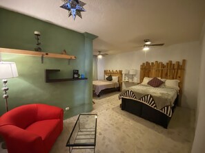 A bedroom with a bed, a red chair, a coffee machine, and a ceiling fan. - AmaneZer Hotel Boutique (San Miguel de Allende)