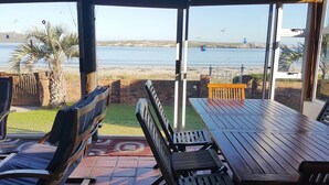 A patio with a view of the sea, wooden furniture, and a brick wall. - Seemansrust, Langebaan 9-sleeper (Langebaan)