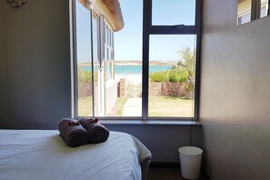 A bedroom with a large window overlooking a beach and a garden. - Seemansrust, Langebaan 9-sleeper (Langebaan)