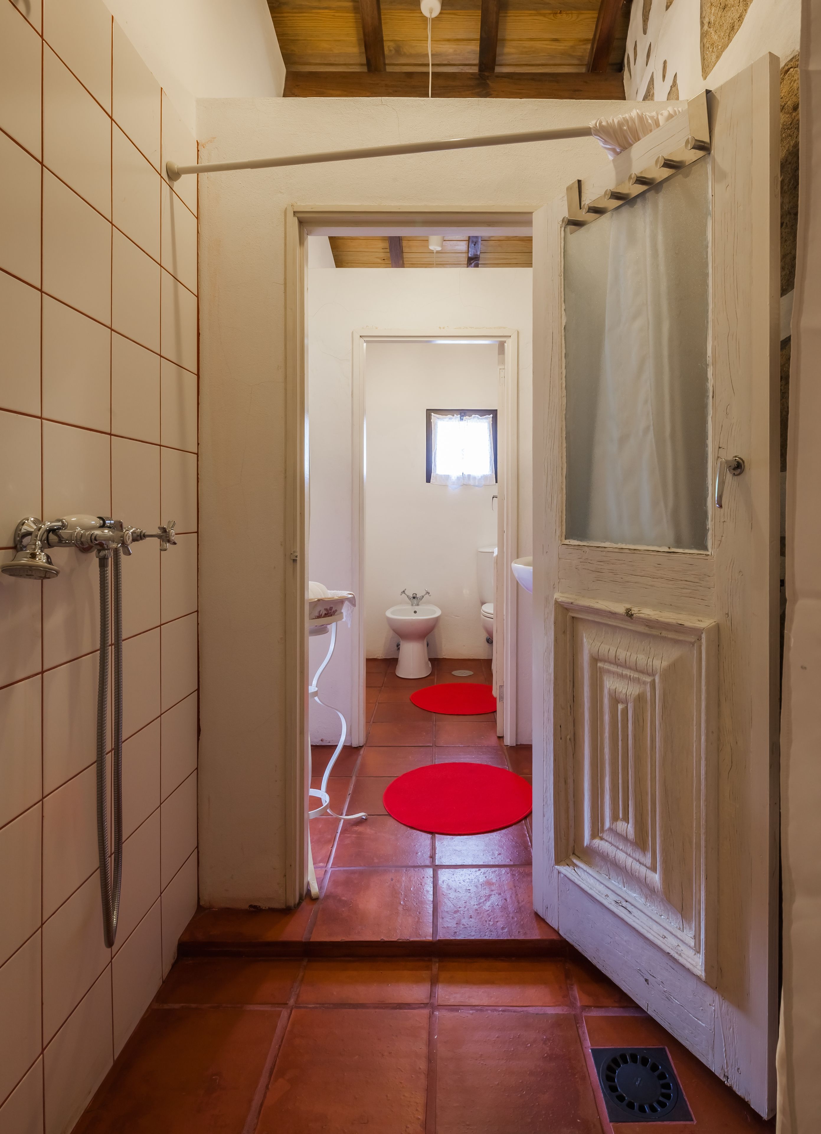 A narrow hallway leading to a bathroom with a toilet, bidet, and sink.