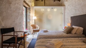 Une chambre à coucher avec un lit, une chaise, une lampe et une vue sur la salle de bain.