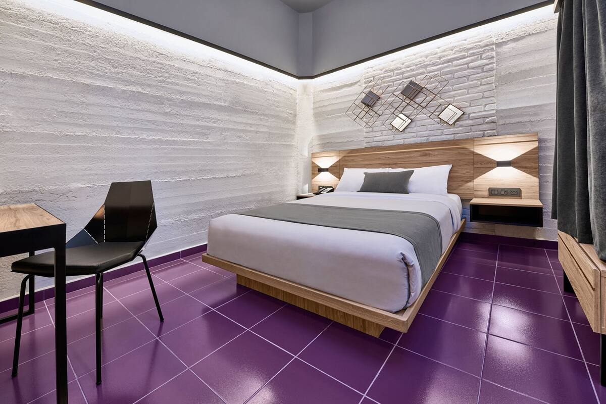 A modern bedroom with a bed, a desk, and a chair.