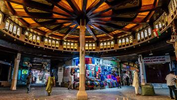 A circular market with a central column, shops on the perimeter, and a variety of goods displayed.