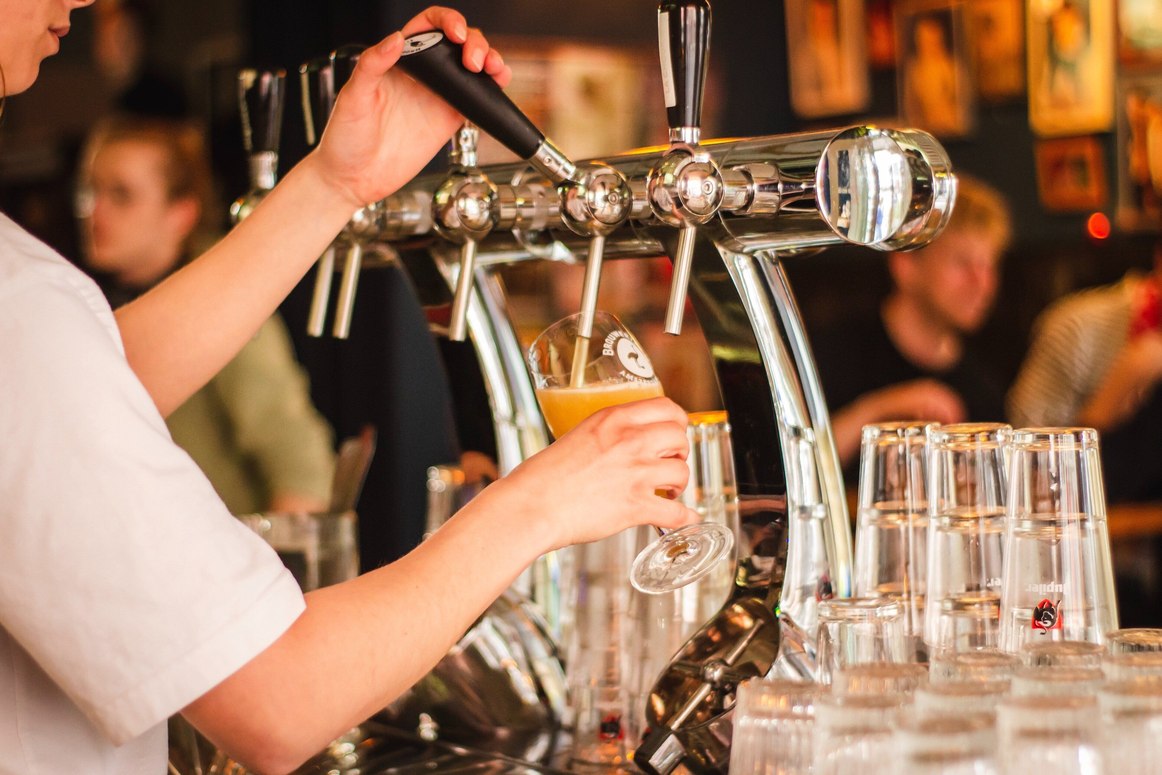 A barista pouring a drink into a glass.