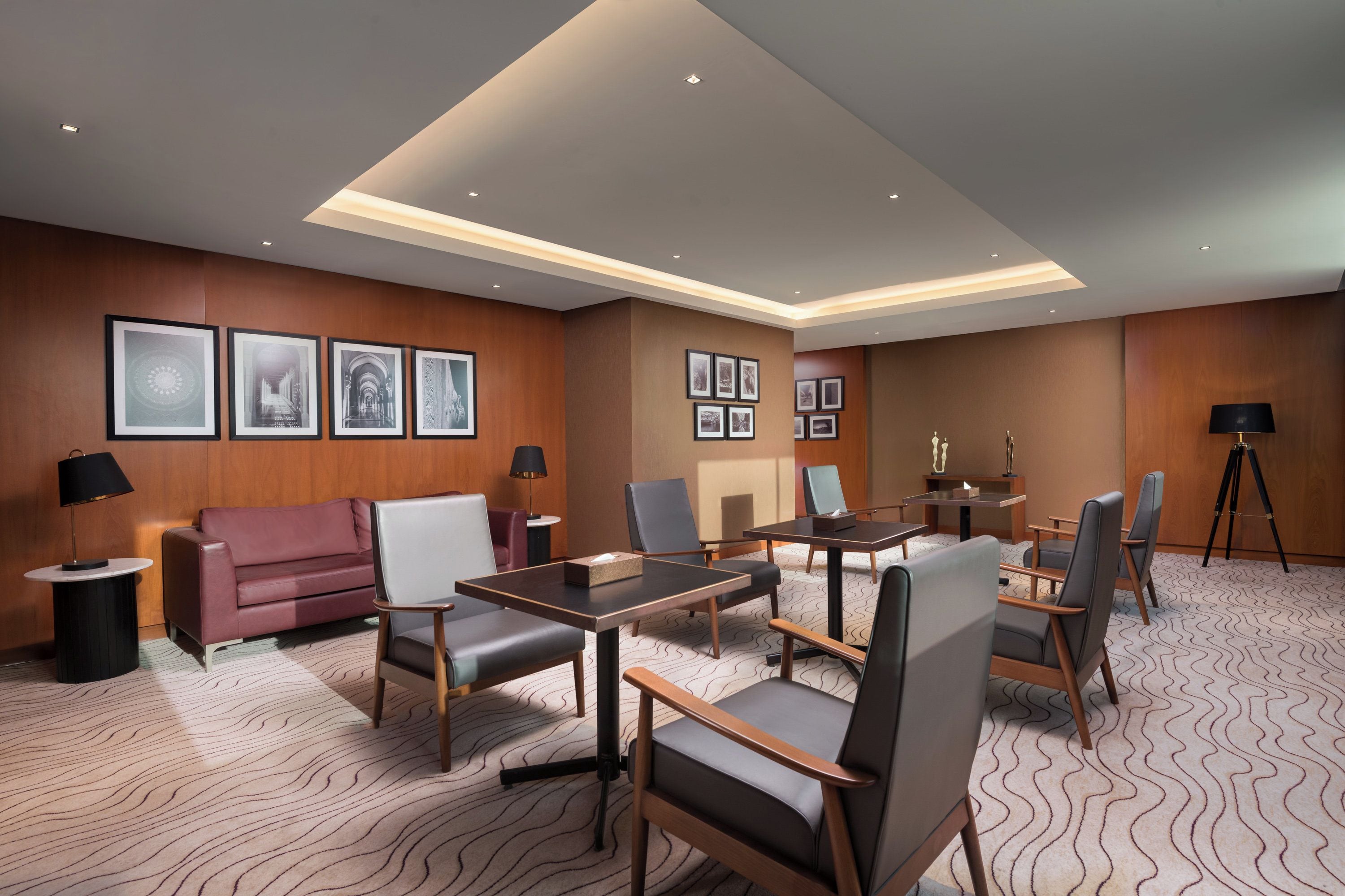 A conference room with a long table, several chairs, a sofa, and framed pictures on the walls.