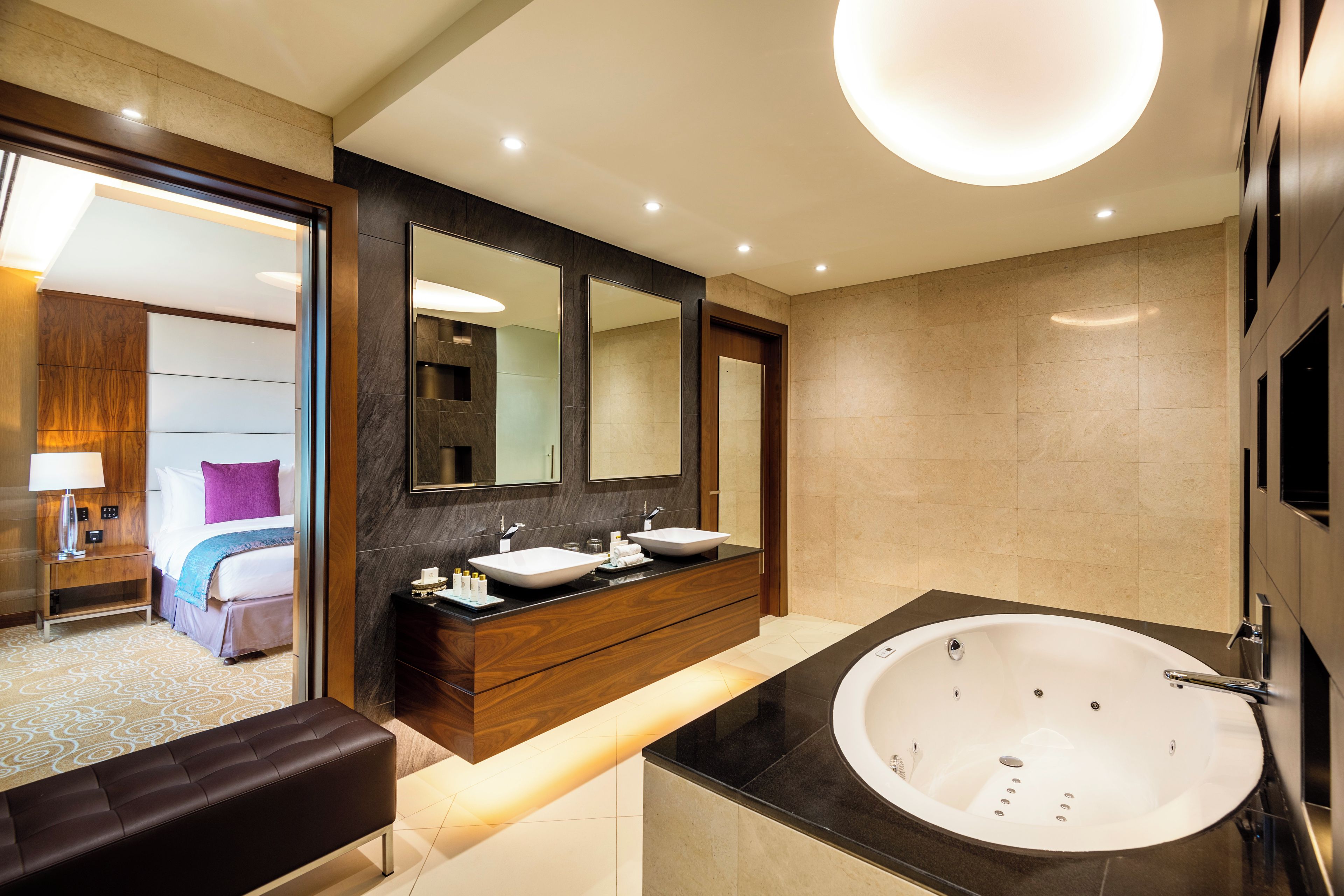 A modern bathroom with a large bathtub, a double vanity with two sinks, and a large mirror above the vanity.