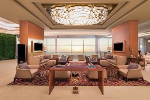 A spacious lounge area with a large chandelier, multiple seating options, and a large window providing a view. - Crowne Plaza Muscat OCEC by IHG (Muscat)