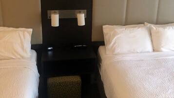 Een hotelkamer met twee eenpersoonsbedden, een nachtkastje en een tafeltje met twee lampen.