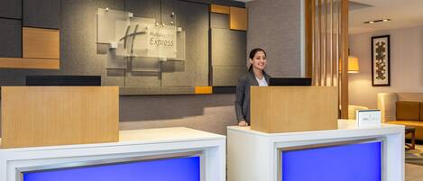 A reception desk with a 'Holiday Inn Express' sign, a wooden partition, and a blue-lit screen.