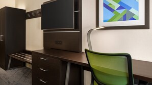 Un escritorio moderno con un televisor de pantalla plana, un cuadro abstracto enmarcado y una silla de malla verde.