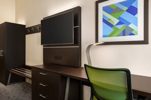 A modern office desk with a flat-screen TV, a framed abstract painting, and a green mesh chair. - Holiday Inn Express & Suites Redding by IHG (Redding)
