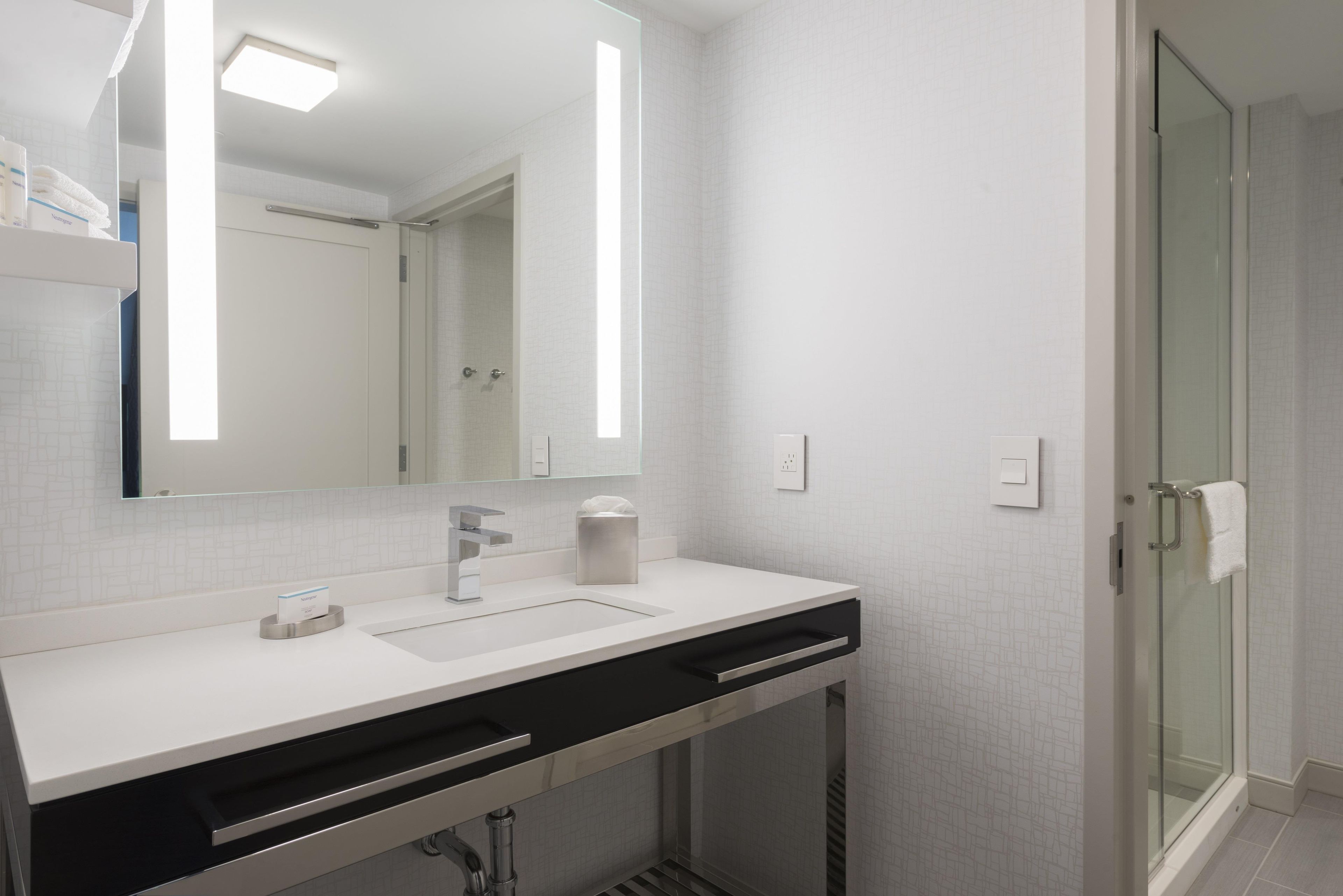 Un bagno moderno con un lavandino bianco, uno specchio e un box doccia in vetro.