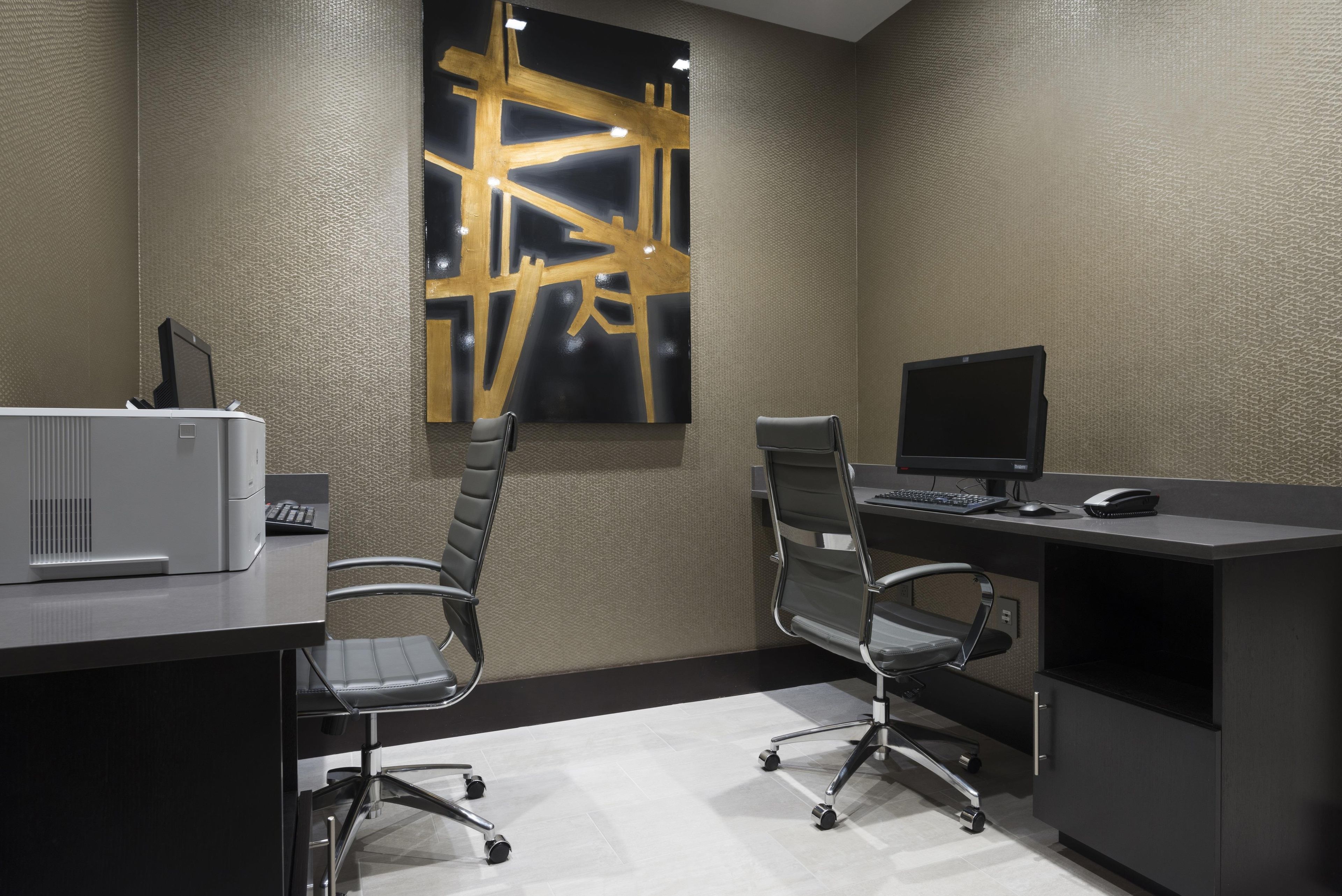 A modern office space with two office chairs, a desk with a computer, and a large abstract painting on the wall.