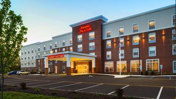 A Hampton Inn & Suites hotel with a brick facade, multiple windows, and a parking lot.