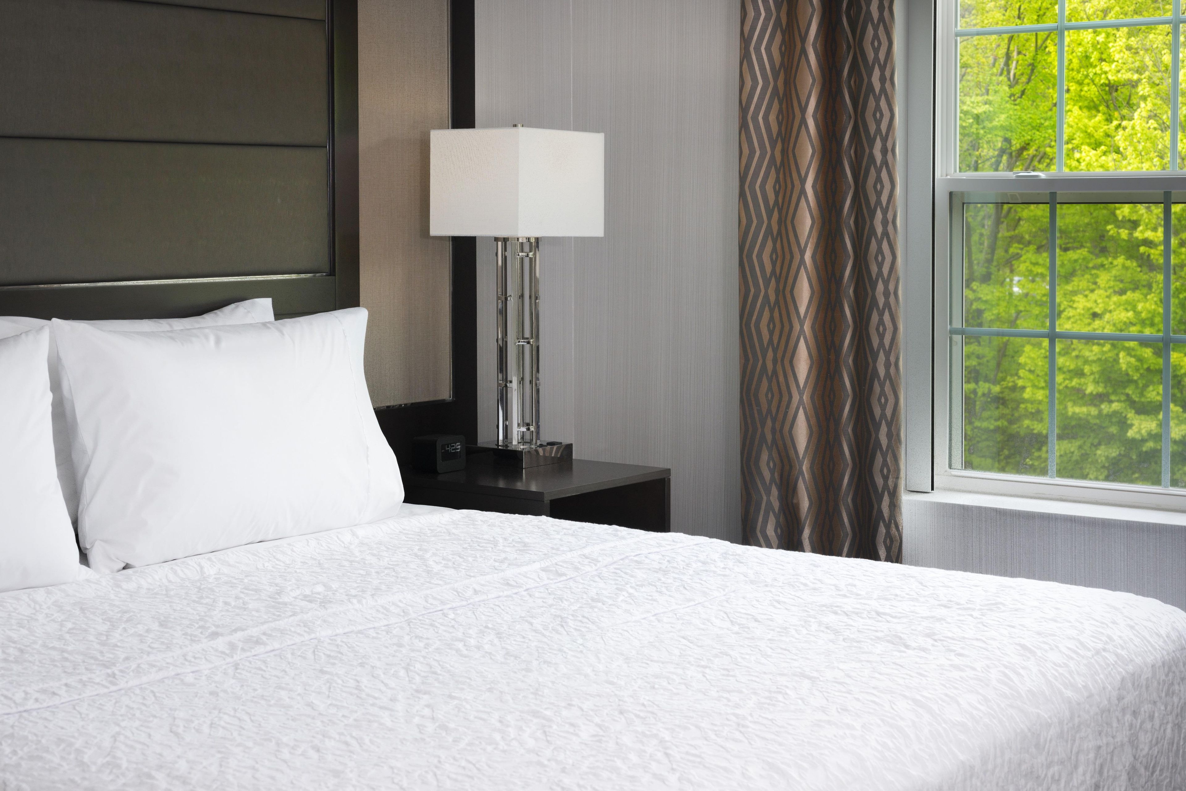 A neatly made bed with white linens in a hotel room.