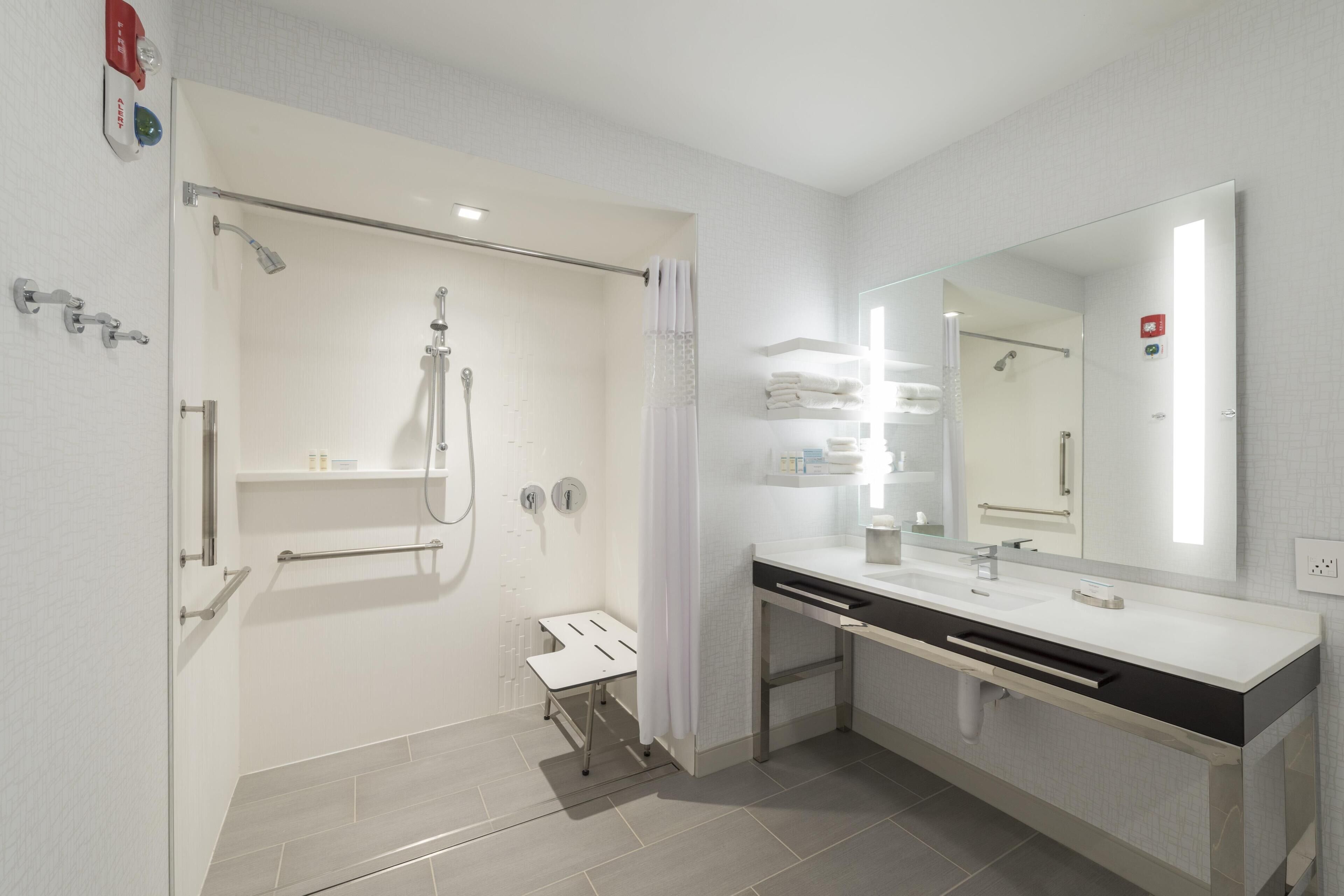 Un baño moderno con ducha, tocador con espejo y retrete.