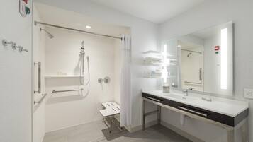 Un baño moderno con ducha, tocador con espejo y retrete.