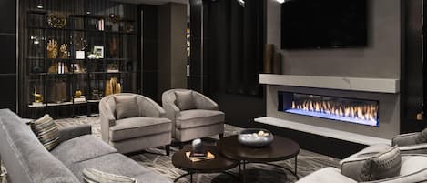 A modern living room with a fireplace, sofas, and a bookshelf.