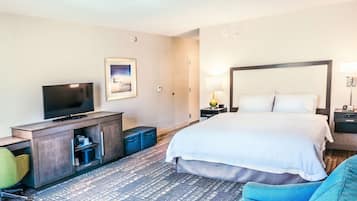A hotel room with a bed, a TV, a desk, a chair, and a lamp.
