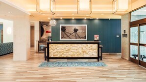 A lobby with a reception desk, a wall-mounted sign, and a framed picture of a Ferris wheel. - Hampton Inn & Suites Mission Viejo (Mission Viejo)