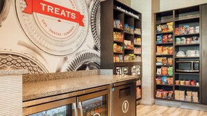 A snack bar with a 'Treats' sign, shelves stocked with snacks and drinks, and a microwave. - Hampton Inn & Suites Mission Viejo (Mission Viejo)