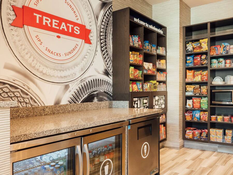 Un bar proposant des collations, avec une enseigne indiquant « Friandises », des étagères remplies de snacks et de boissons, et un four à micro-ondes.