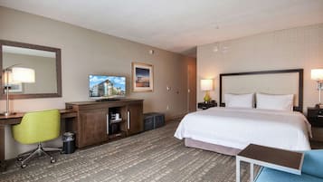 Una habitación de hotel con cama, escritorio, silla, televisor y una mesita.